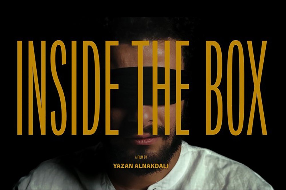 Schriftzug "Inside the box" in Großbuchstaben. Im Hintergrund ist das Gesicht eines jungen Mannes erkennbar, dem die Augen verbunden sind. 