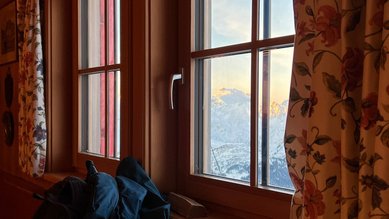 Blick aus dem Fenster auf verschneite Berggipfel im Sonnenschein