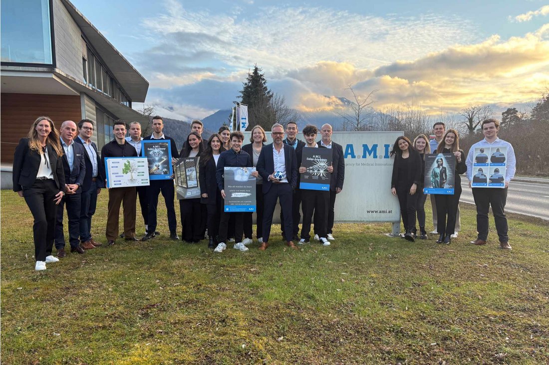 Gruppenbild auf einer Wiese neben einem Gebäude, einige Personen halten Plakate und Poster hoch.