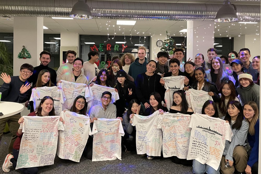 Gruppenbild, auf dem viele ihre beschrifteten T-Shirts hochhalten: Die Internationals und ihre Buddys bei der Weihnachtsfeier.